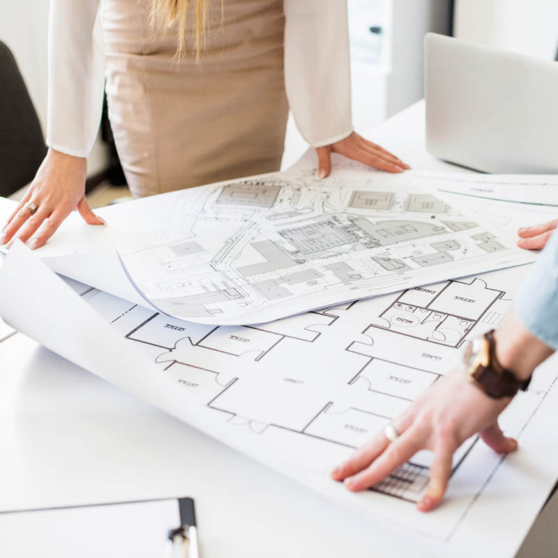 a man and a woman checking the design plans for a real estate